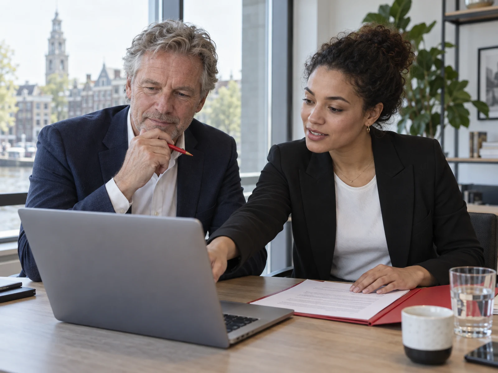 Twee medewerkers bespreken MijnZaak op een laptop.