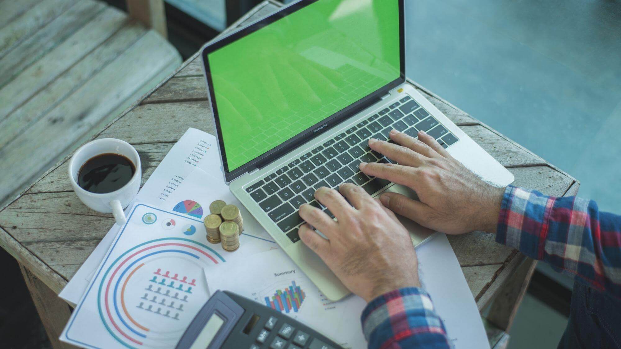 A man using a laptop computer sitting on top of a table